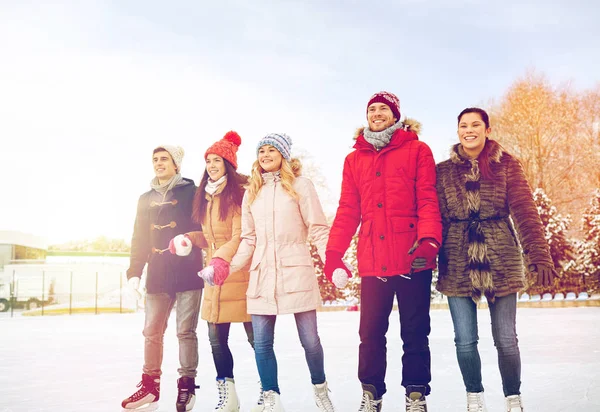 Happy friends ice skating on rink outdoors — Stock Photo, Image