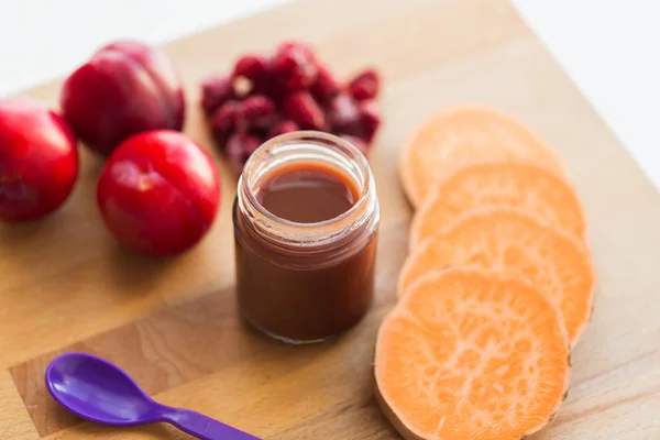 Fruit puree or baby food in jar and feeding spoon — Stock Photo, Image