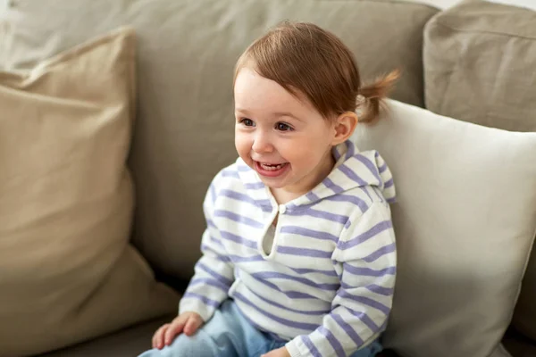 Happy smiling baby girl sitting on sofa at home — Stock Photo, Image