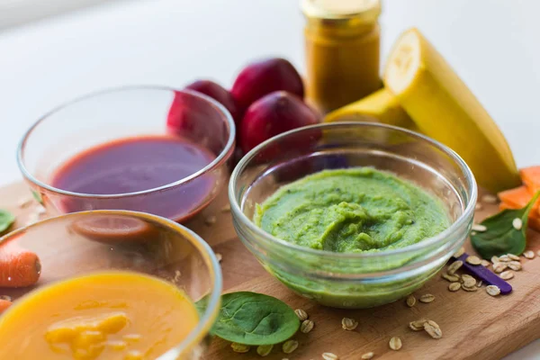 Puré de verduras o alimentos para bebés en cuencos de vidrio Imagen de archivo