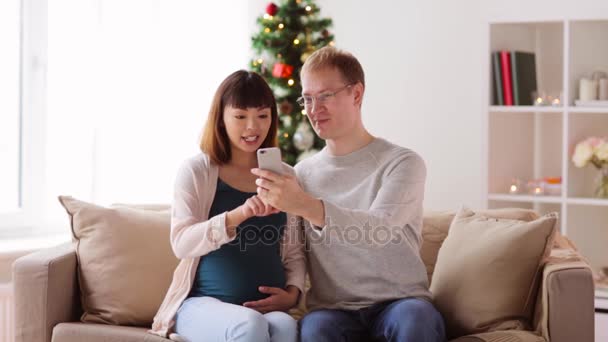 Homem e mulher grávida com smartphone no Natal — Vídeo de Stock