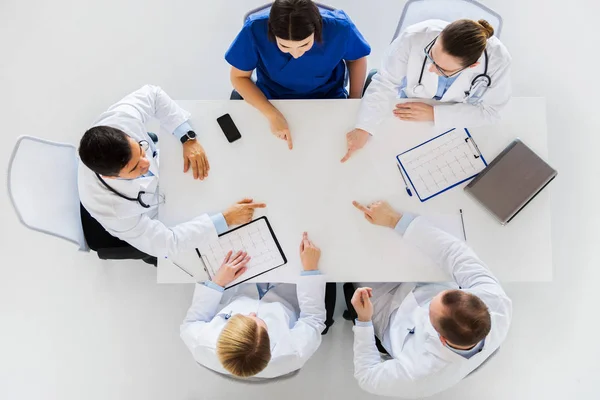 Skupina lékařů s vezmeme si prášek pracuje u stolu — Stock fotografie