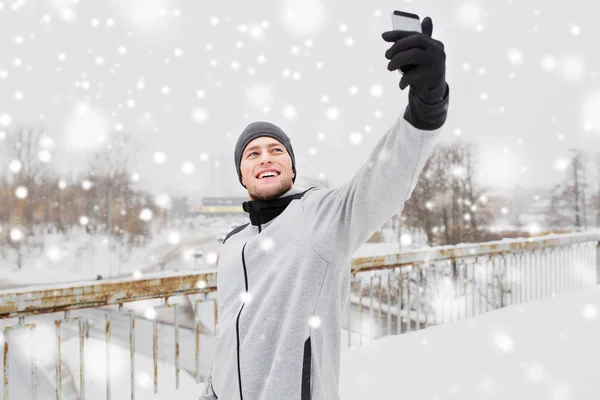 Мужчина делает селфи со смартфоном зимой — стоковое фото