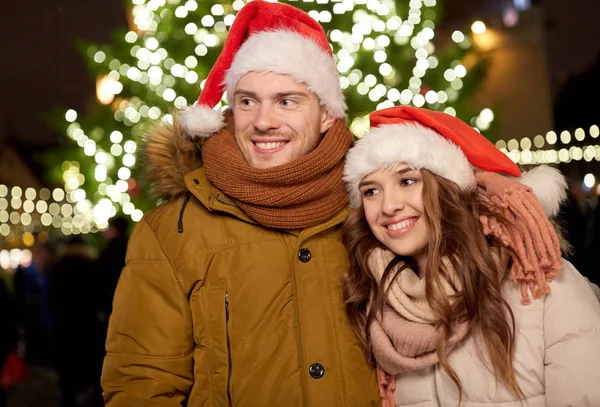 Heureux couple dans chapeaux de Père Noël à l'arbre de Noël — Photo