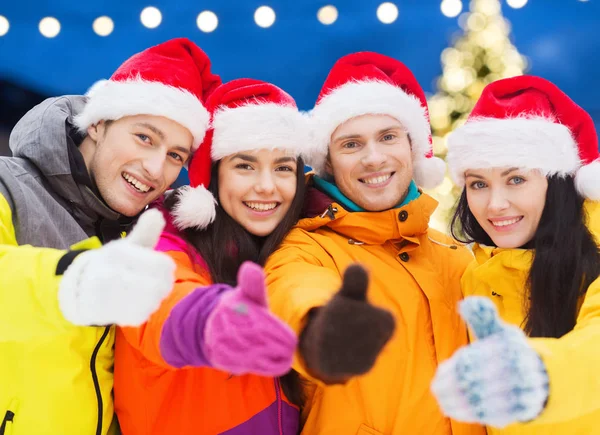 Happy vrienden in santa hoeden en skipakken buitenshuis — Stockfoto