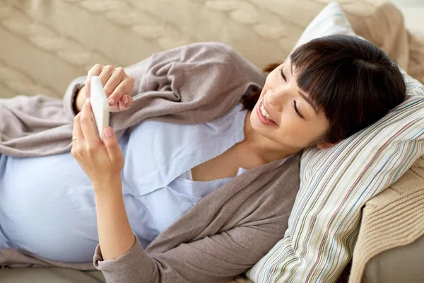 Mulher grávida feliz com smartphone em casa — Fotografia de Stock