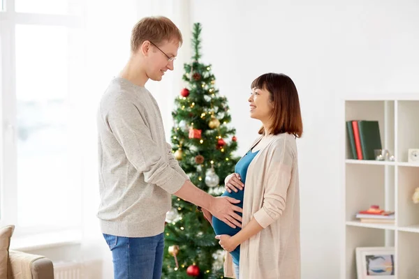 Pregnant wife with husband at home at christmas — Stock Photo, Image