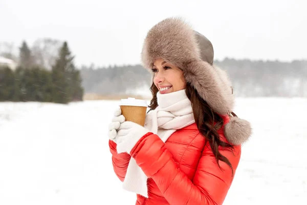 Lycklig kvinna i vinter päls hatt med kaffe utomhus — Stockfoto