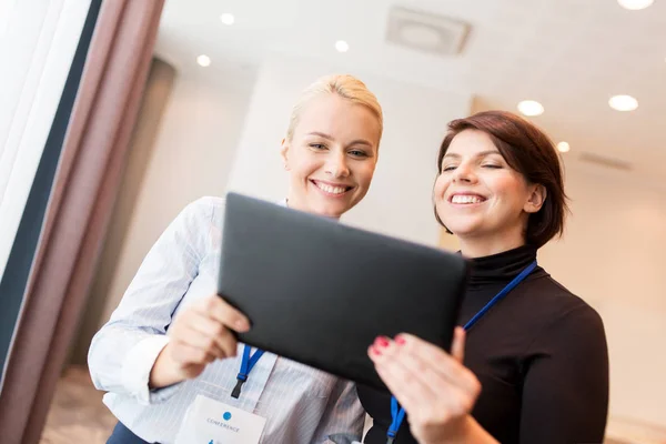 Businesswomen with tablet pc and conference badges — Stock Photo, Image