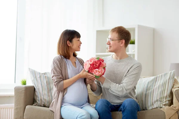 Marido feliz dando flores para sua esposa grávida — Fotografia de Stock