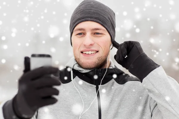 Hombre feliz con auriculares y smartphone en invierno —  Fotos de Stock