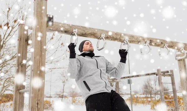 Jovem exercitando-se na barra horizontal no inverno — Fotografia de Stock