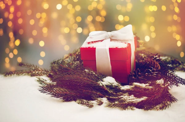 Cadeau de Noël et couronne de sapin avec des cônes sur la neige — Photo