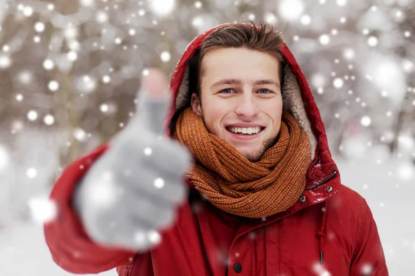 Homem feliz em casaco de inverno mostrando polegares para cima — Fotografia de Stock