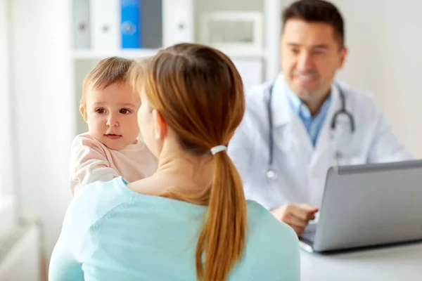 Donna con bambino e medico con laptop in clinica — Foto Stock