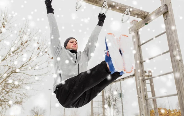 Jonge man uitoefenen op horizontale balk in de winter — Stockfoto