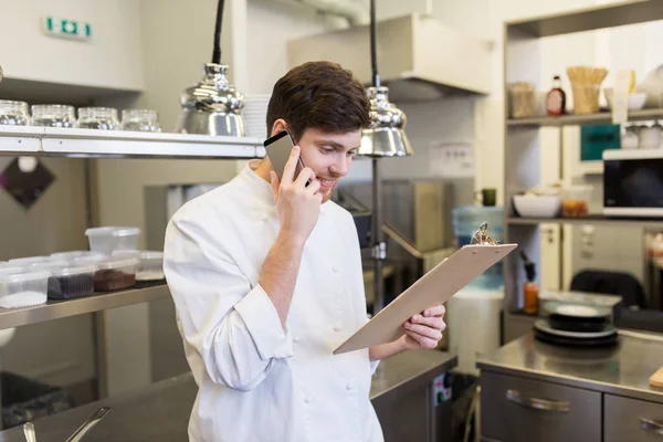 Kocken cook uppmanar smartphone på restaurang kitchen — Stockfoto