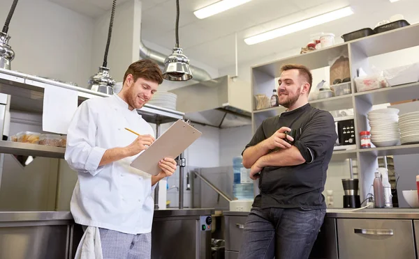 Szczęśliwy uśmiechający się szef kuchni i gotować w restauracji kitchen — Zdjęcie stockowe