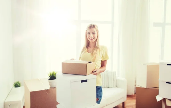 Lachende jonge vrouw met kartonnen doos thuis — Stockfoto