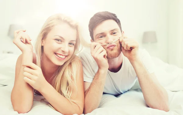 Casal feliz deitado na cama em casa — Fotografia de Stock