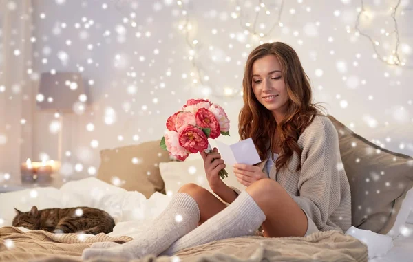 Gelukkige vrouw met bloemen en wenskaart thuis — Stockfoto