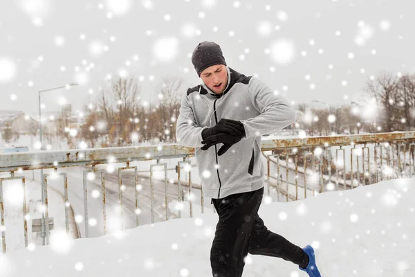 Hombre con auriculares corriendo a lo largo del puente de invierno —  Fotos de Stock