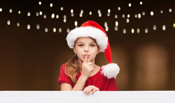 Girl in santa hat with board making hush gesture — Stock Photo, Image