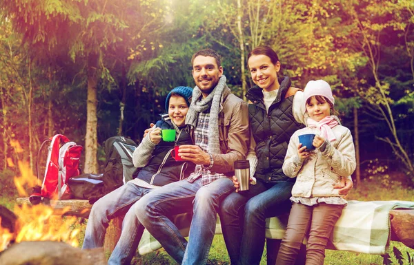 Famiglia felice bere tè caldo al fuoco del campo — Foto Stock