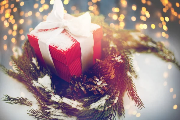 Presente de Natal e grinalda de abeto com cones na neve — Fotografia de Stock