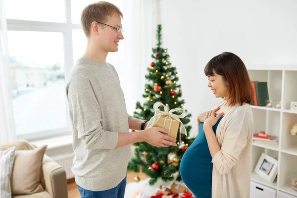 Муж дарит рождественский подарок беременной жене — стоковое фото