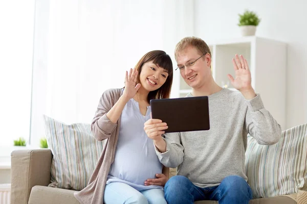 Муж и беременная жена с планшетным ПК дома — стоковое фото