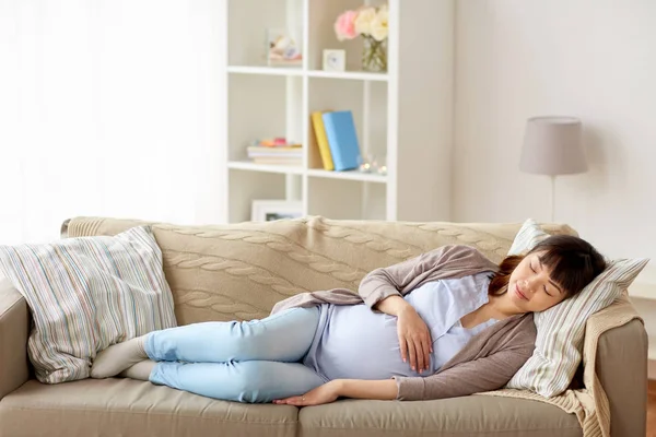Счастливая беременная женщина спит на диване дома — стоковое фото