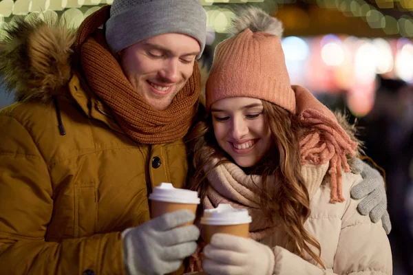 Gelukkige paar met koffie over Kerstverlichting — Stockfoto