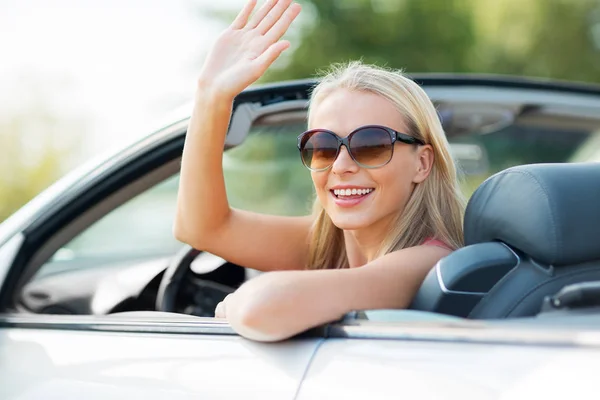 Feliz joven mujer en coche convertible agitando la mano — Foto de Stock