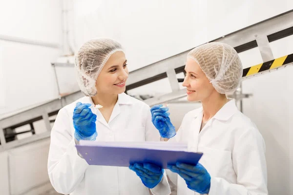 Mujeres tecnólogos degustación de helado en la fábrica — Foto de Stock