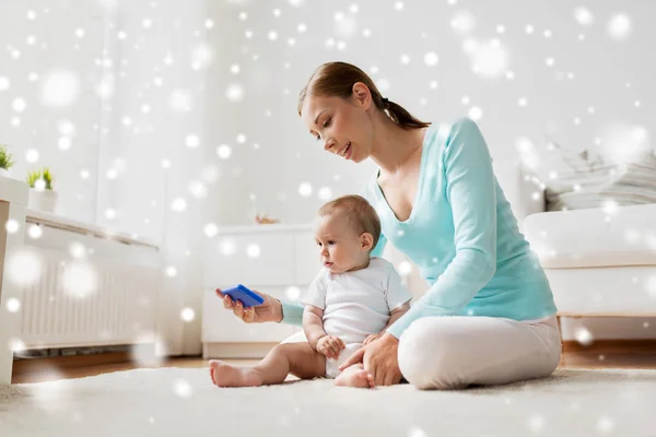 Happy mother showing smartphone to baby at home — Stock Photo, Image