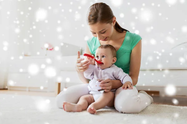 Mãe com colher alimentando bebê em casa — Fotografia de Stock