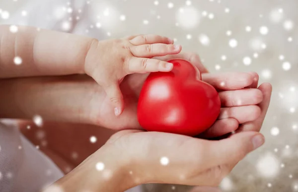 Close up of baby and mother hands with red heart — Stock Photo, Image