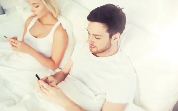 Coppia con smartphone a letto — Foto Stock