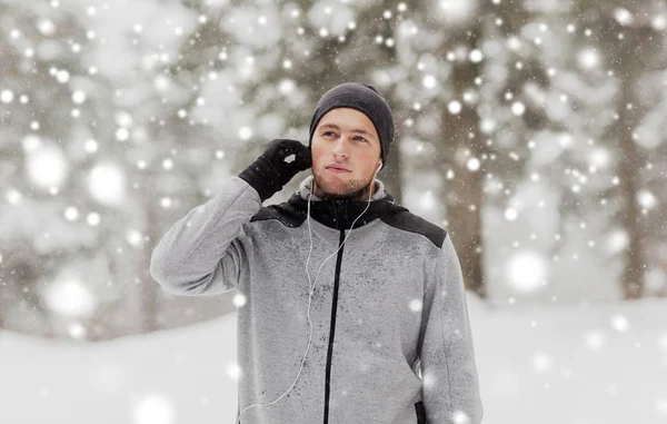 Спортивный человек с наушниками в зимнем лесу — стоковое фото