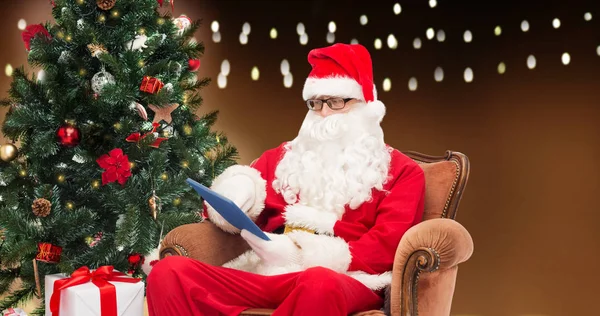Санта-Клаус с планшетным ПК и елкой — стоковое фото
