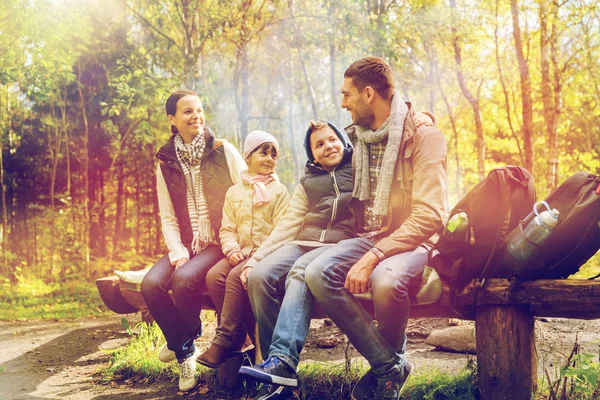 Feliz familia sentada en el banco y hablando en el campamento —  Fotos de Stock