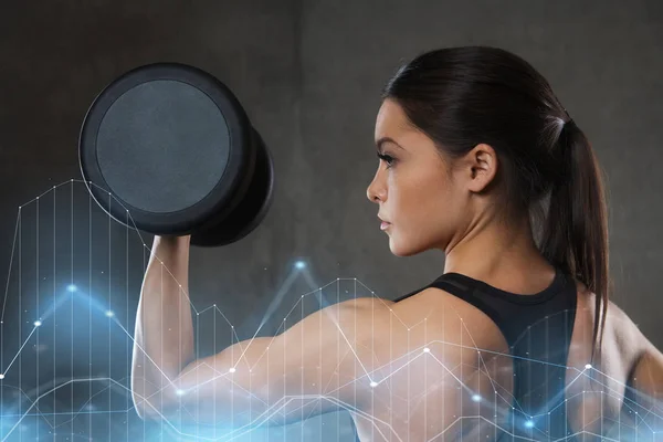 Mujer joven flexionando los músculos con pesas en el gimnasio —  Fotos de Stock