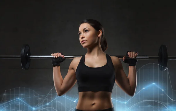 Mujer joven flexionando los músculos con barra en el gimnasio —  Fotos de Stock