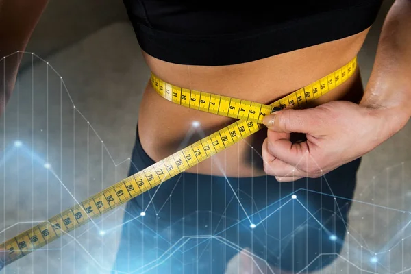 Close up of woman measuring waist by tape in gym — Stock Photo, Image