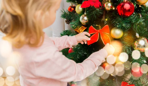 Nahaufnahme eines kleinen Mädchens, das den Weihnachtsbaum schmückt Stockfoto