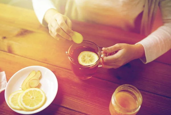 Menutup wanita menambahkan jahe ke teh dengan lemon — Stok Foto