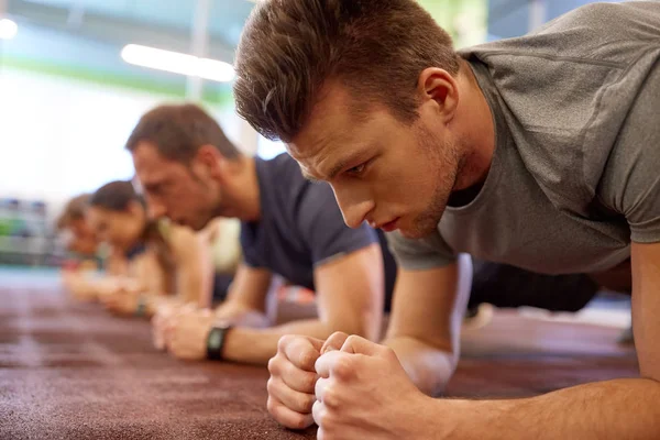 Человек делает упражнения на доске на групповых тренировках в тренажерном зале — стоковое фото