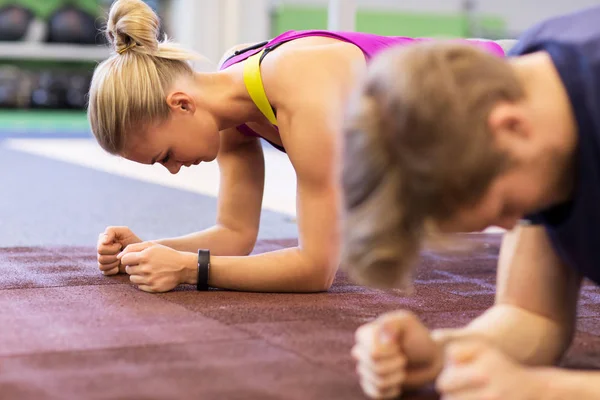 Kvinna och man gör plankan övning i gymmet — Stockfoto