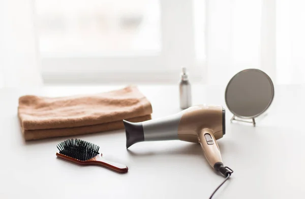 Secador de cabelo, escovas de cabelo, espelho e toalha — Fotografia de Stock